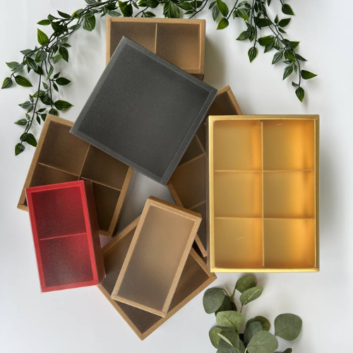 Mooncake Drawer Boxes in assorted colours with some plants in the background
