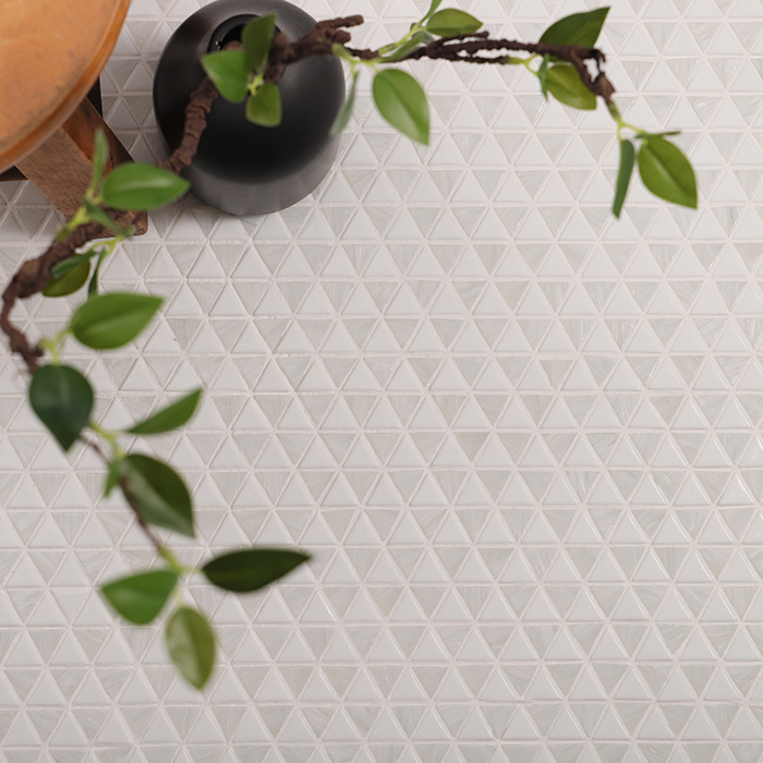 White triangle checkerboard glass mosaic tiles on a floor beneath a plant.