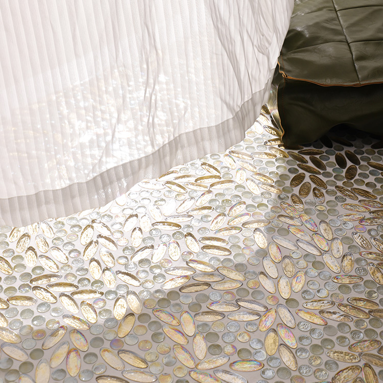 Oval gold and circular white glass mosaic tiles in an irregular pattern on the floor with a curtain