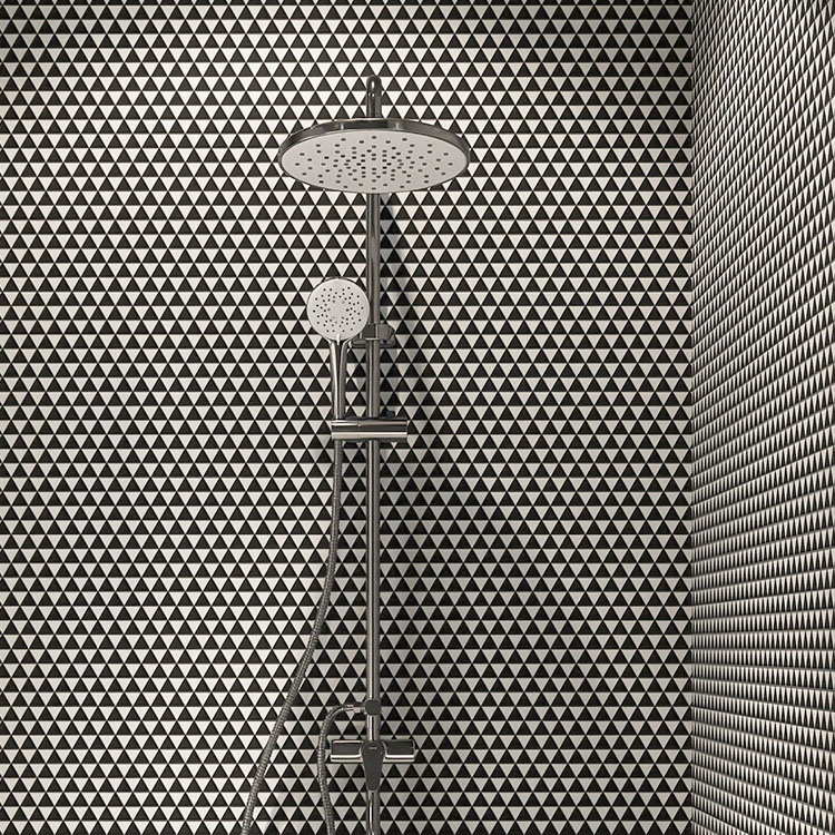 Black and white triangle glass mosaic tiles on the shower wall with a showerhead