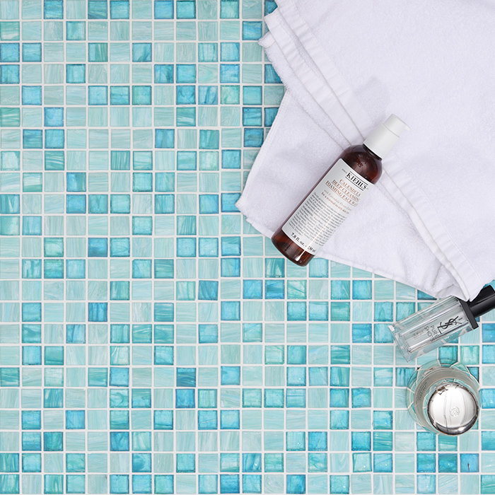 Front view of emerald green glass mosaic tiles with a white towel beside them.