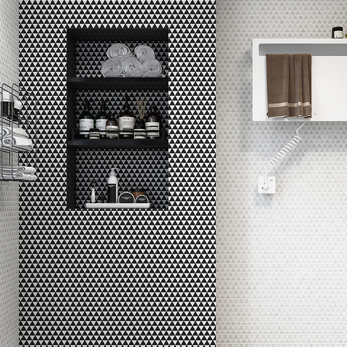 Bathroom wall and niche featuring black and white triangle-shaped mosaic tiles.