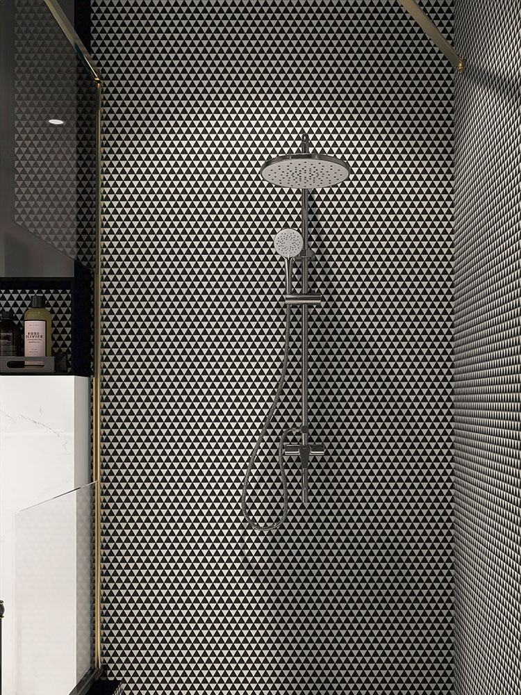 Black and white triangular mosaic tiles on the shower wall with the showerhead.