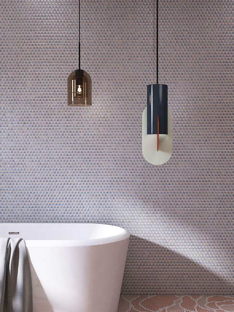 Light blue triangle mosaic tiles on a bathroom wall with a white bathtub and pendant lights