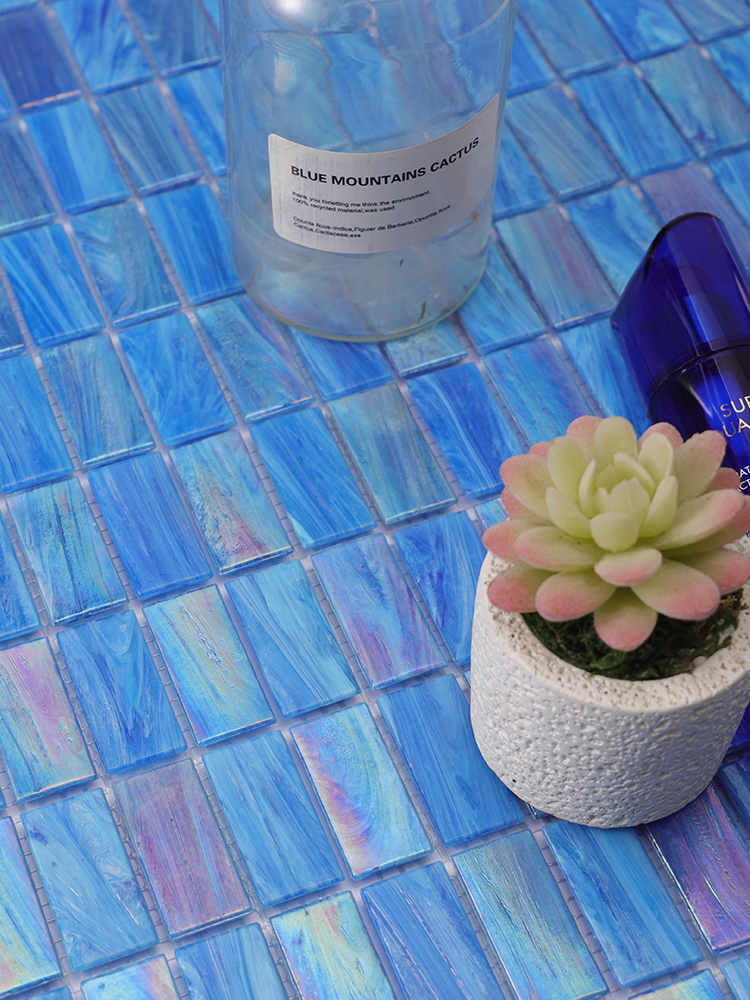The iridescent blue mosaic tiles bring a vibrant and shimmering effect to the floor, complemented by decorative plastic flowers and neatly arranged skincare products.