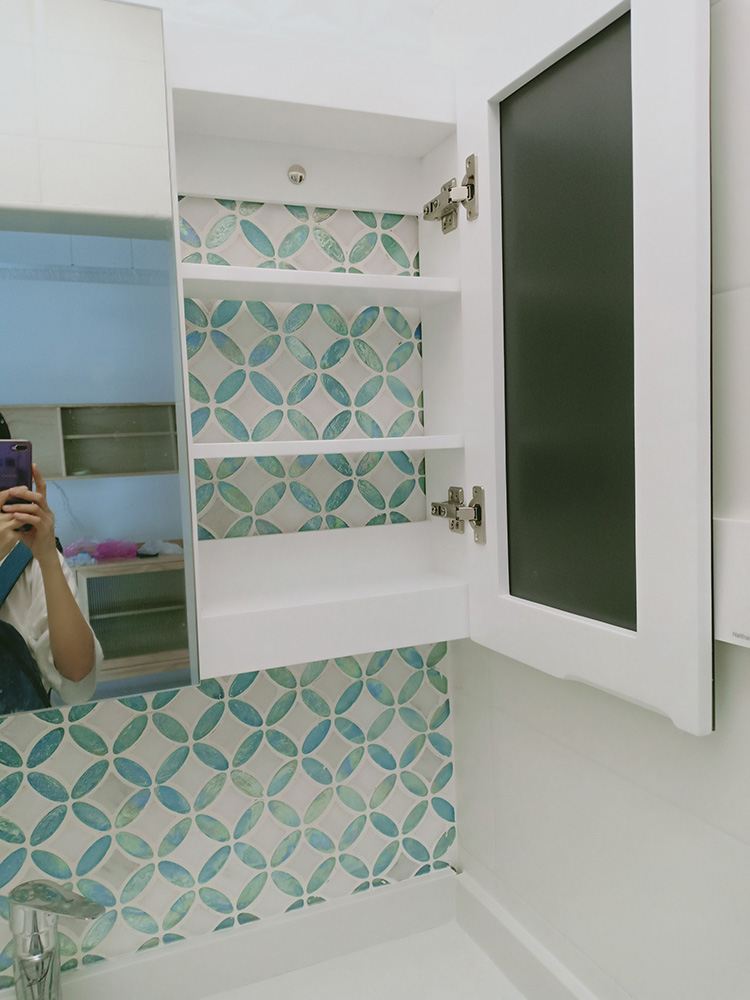 The blue and white mosaic backsplash brings a refreshing and clean aesthetic to the sink area, adding a stylish contrast for a modern bathroom design