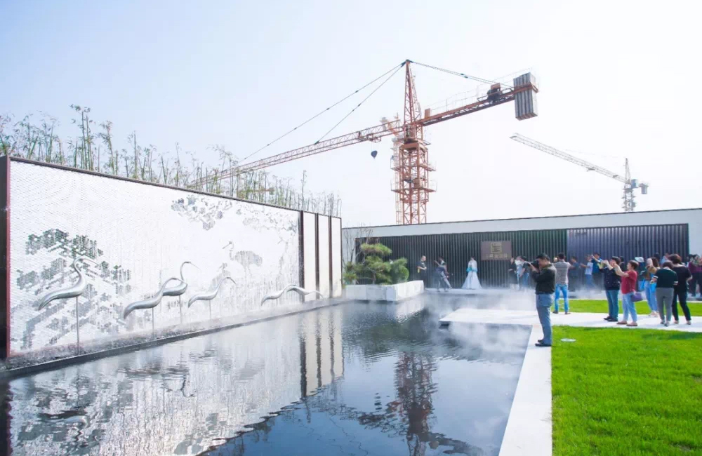 Crane backdrop made of silver hexagonal mosaic tiles, with visitors taking photos