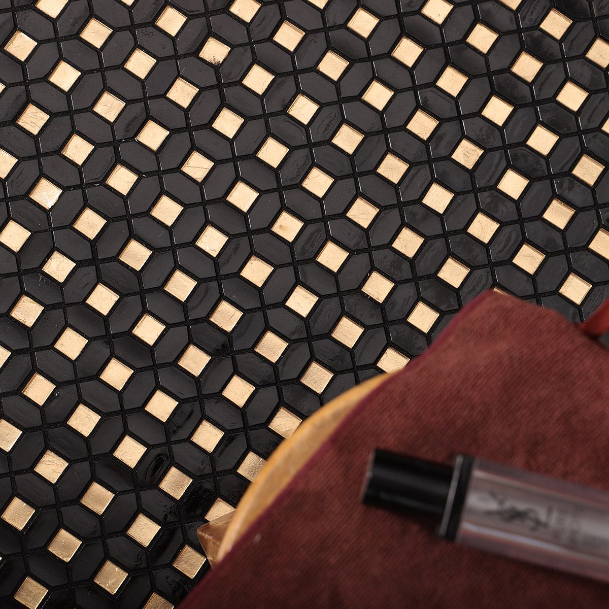 Detail of black mini picket and square gold glass mosaic tiles on the floor.