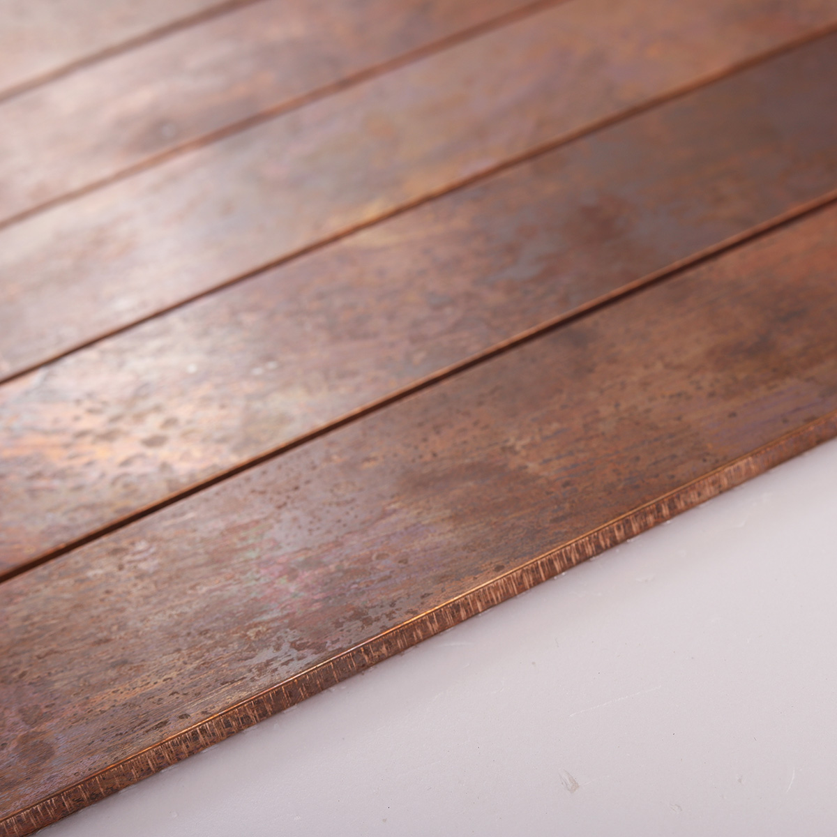 Side close-up of copper rust matte brick metal mosaic tiles, showing thickness