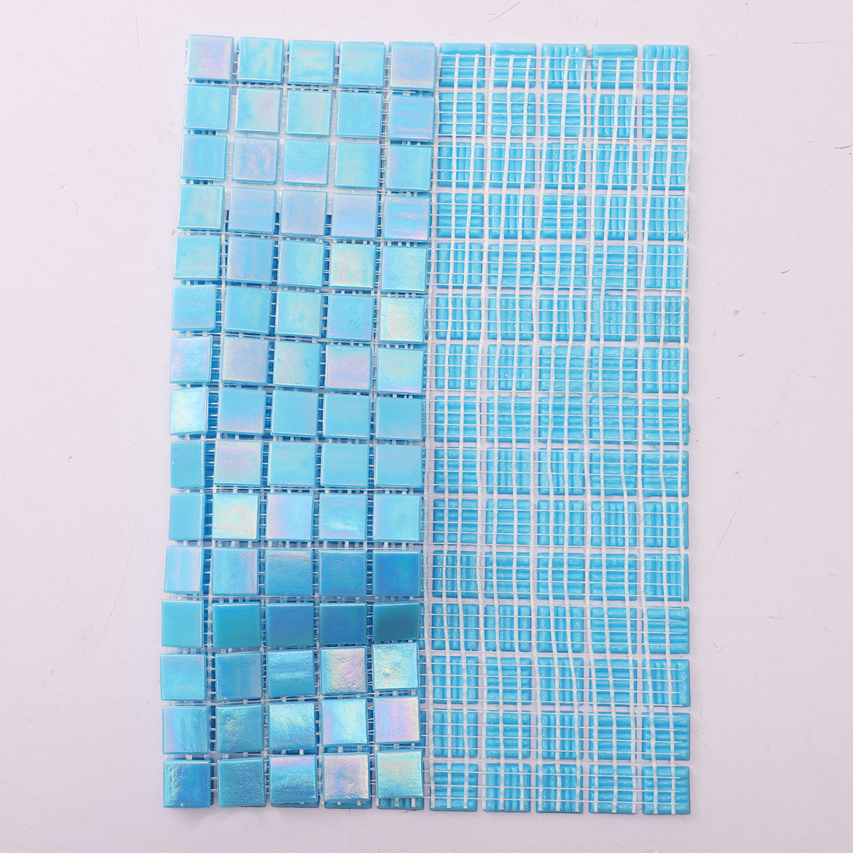 Back side of iridescent sky blue square glass mosaic tiles, showing fold and mesh mounted.
