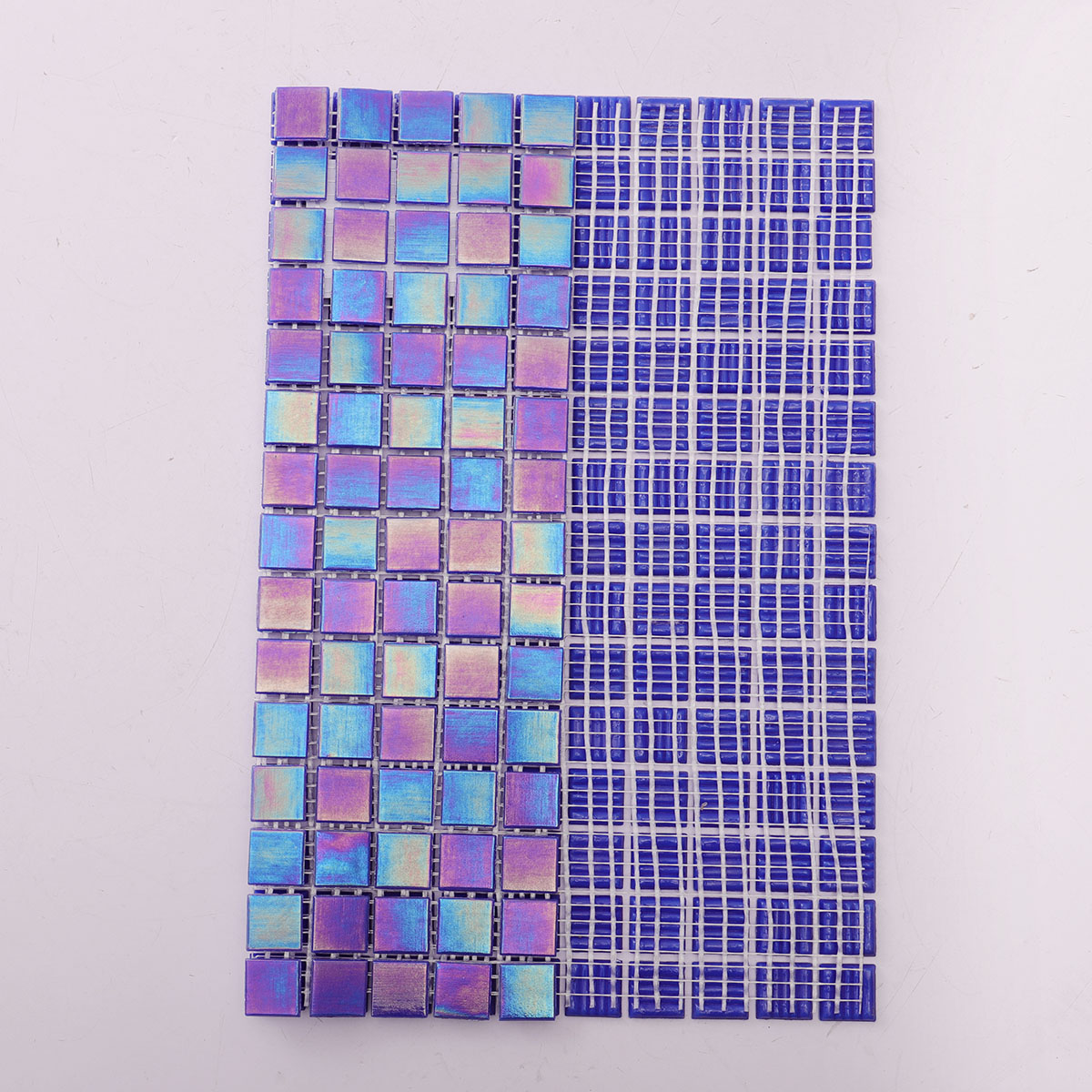 Back side of cobalt blue iridescent square glass mosaic tiles, showing fold and mesh mounted.