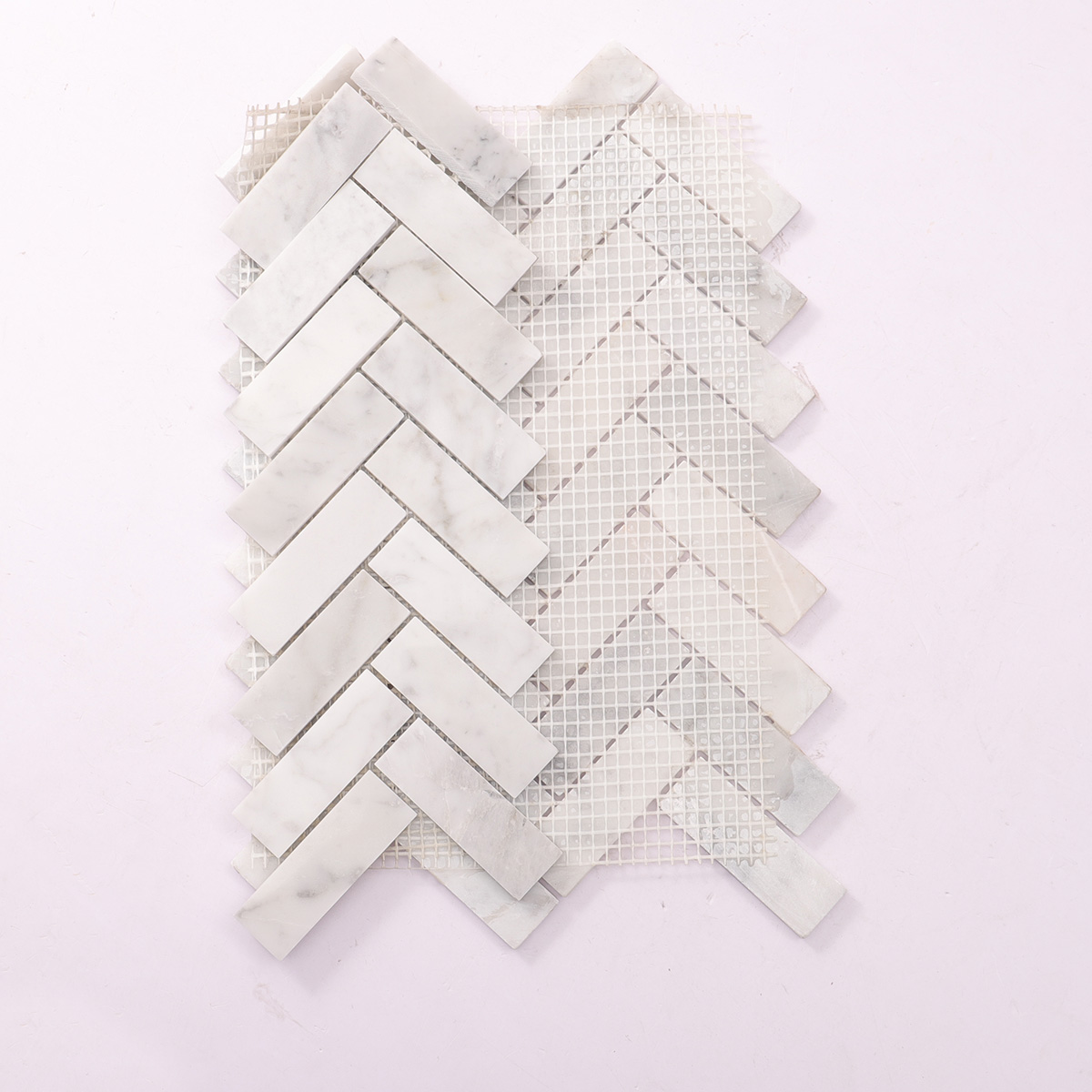 Folded back side of polished herringbone Carrara white marble mosaic tiles.