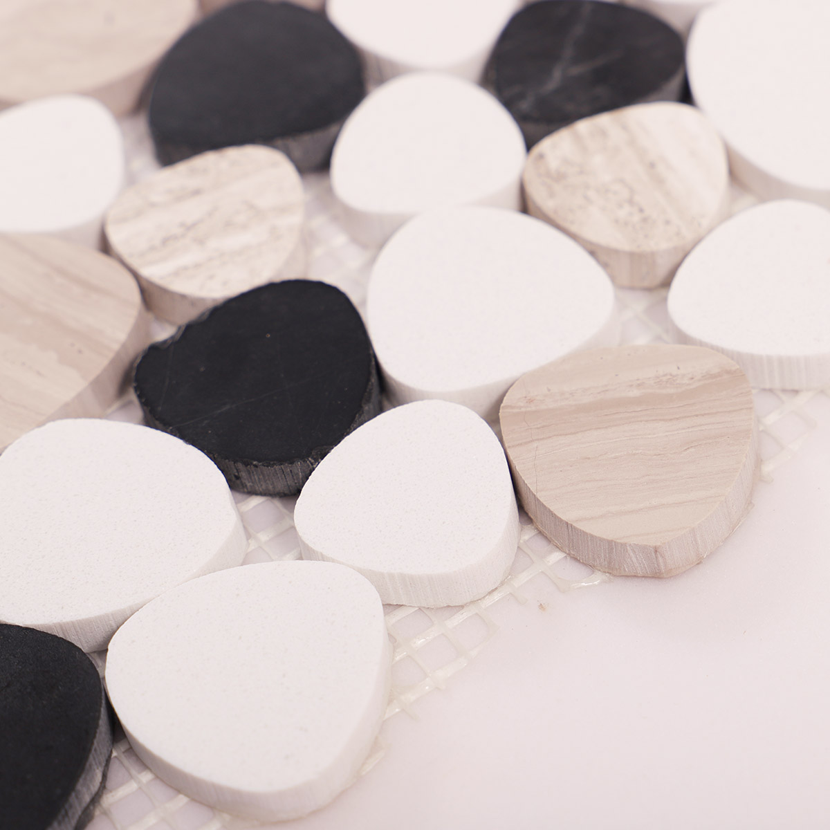Side close-up view of white and black flat pebble stone mosaic tiles, showing texture and thickness.