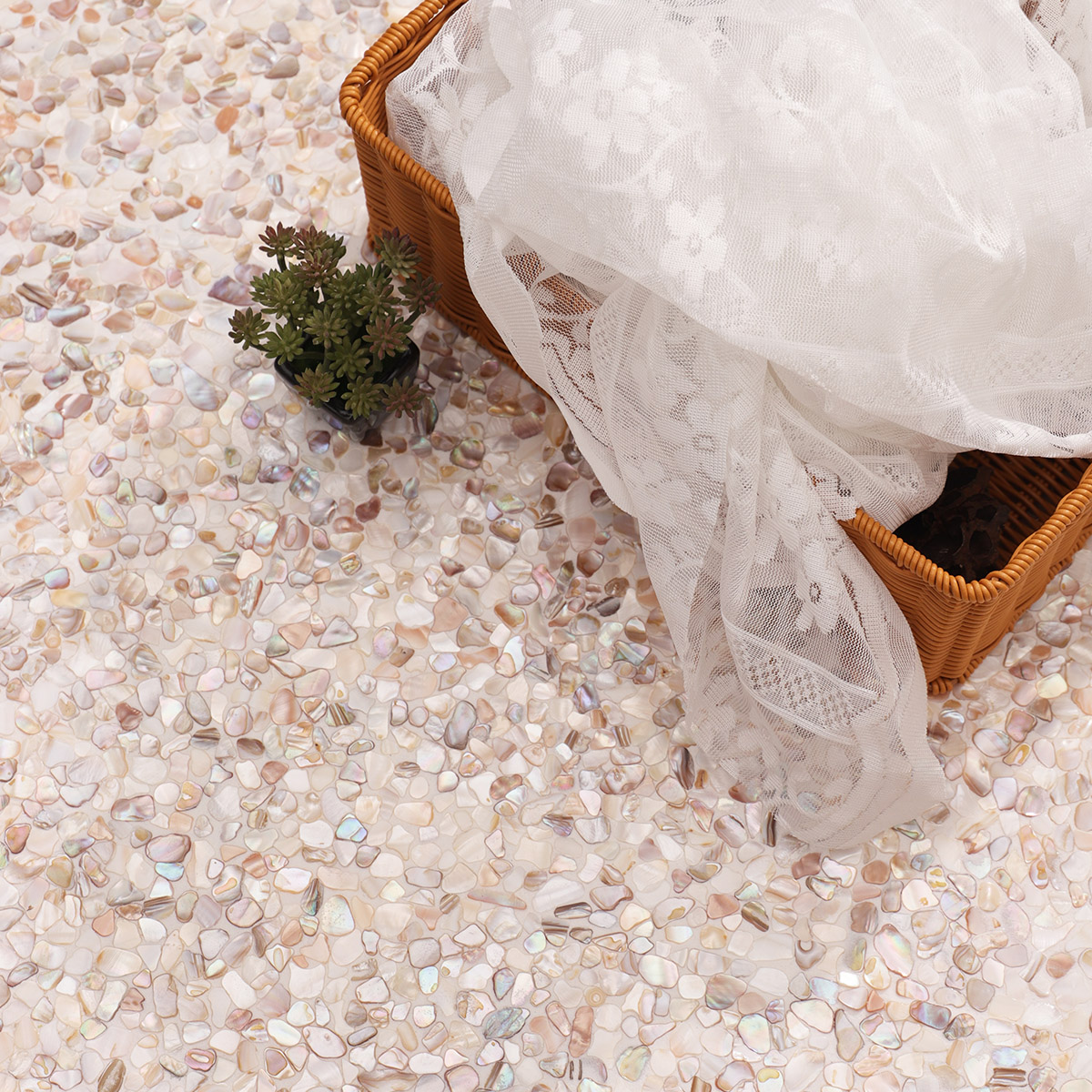 Close-up of irregular mother of pearl shell fragments in pink and white hues with plants.