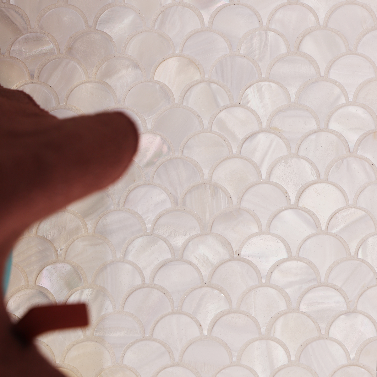 White fish scale mother of pearl mosaic tiles arranged on the floor with decorative items. 