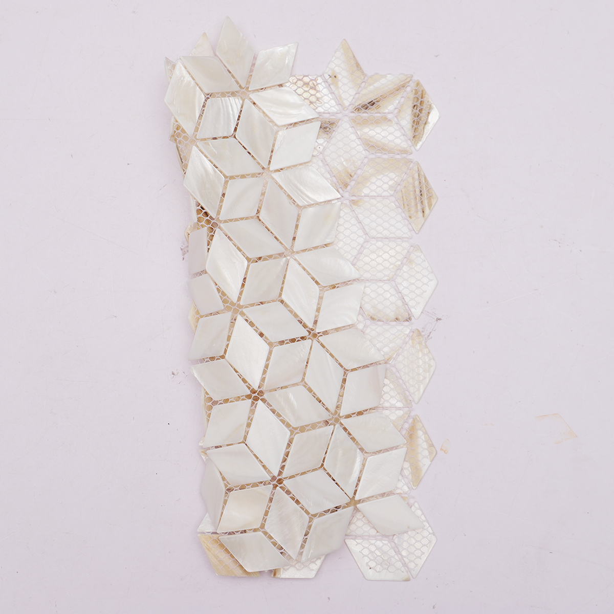A rolled-up sheet of white mother of pearl diamond mosaic tiles.