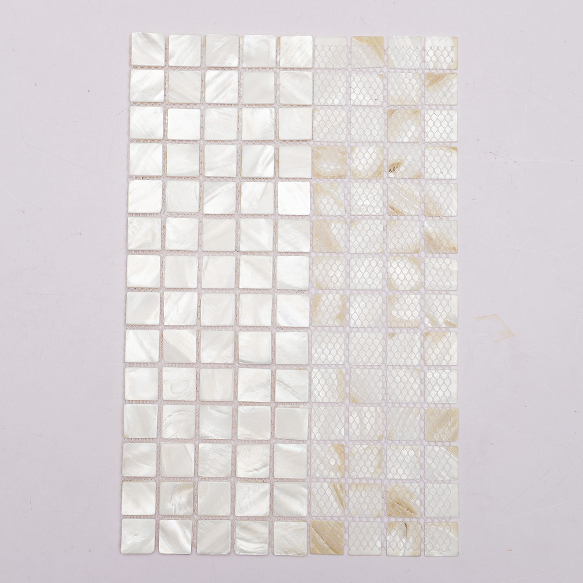 Back side of white mother of pearl square tiles on a sheet with fold.