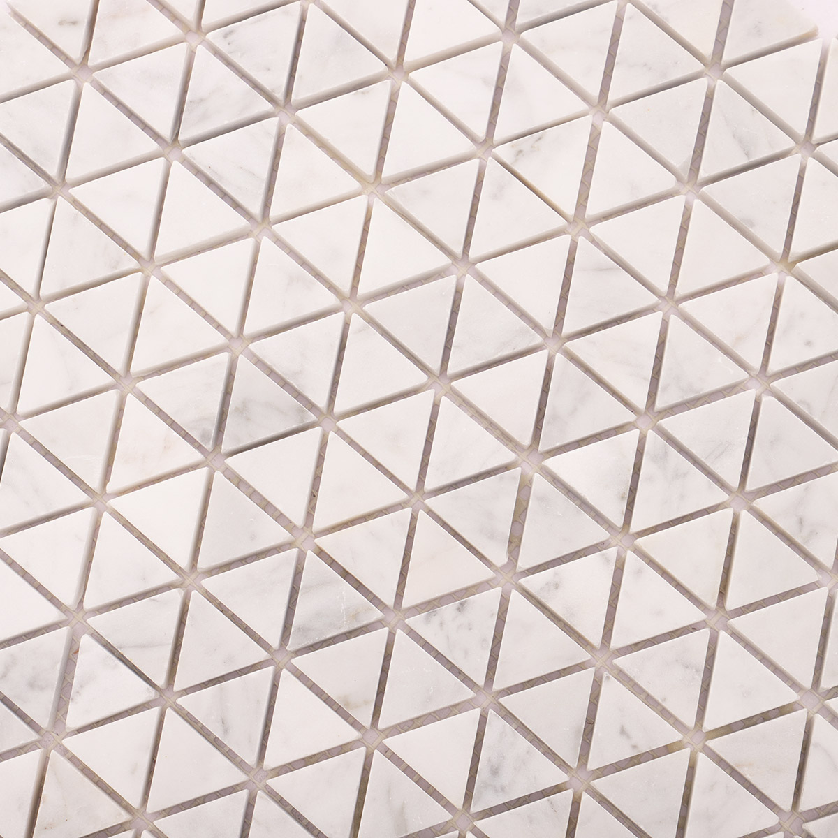 Close-up view of Carrara white geometric triangle marble mosaic tiles.