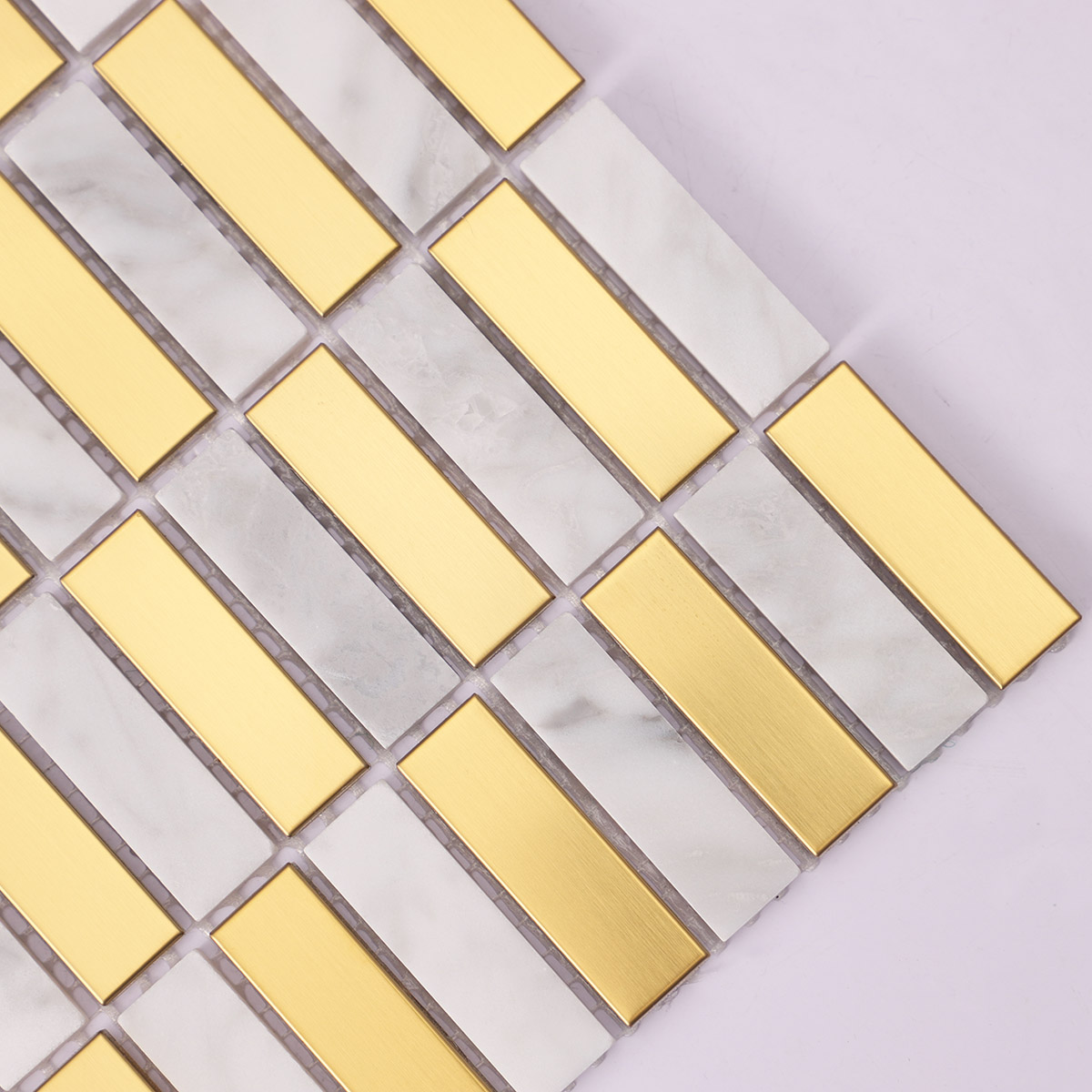 Macro close-up of gold metal and Carrara white marble mosaic tiles.