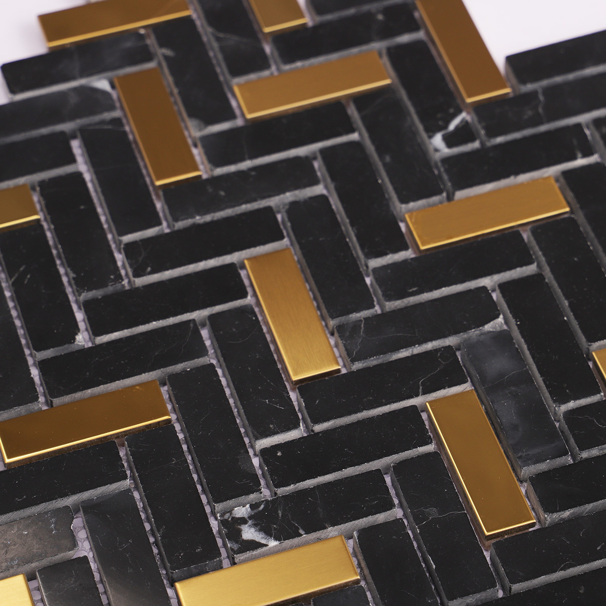 Detailed close-up of black marble and gold metal gradient mosaic tiles.
