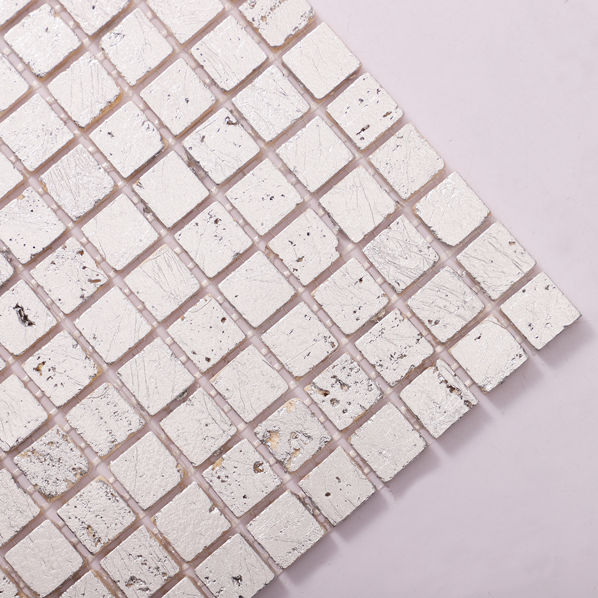 Detailed close-up of silver foil travertine mosaic wall tiles.