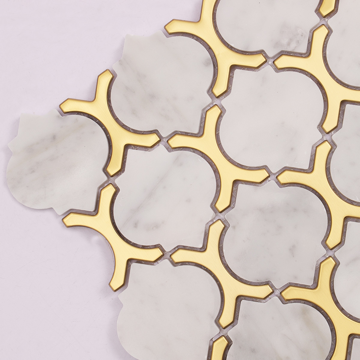 Close-up of Carrara white marble and gold metal arabesque mosaic tiles.