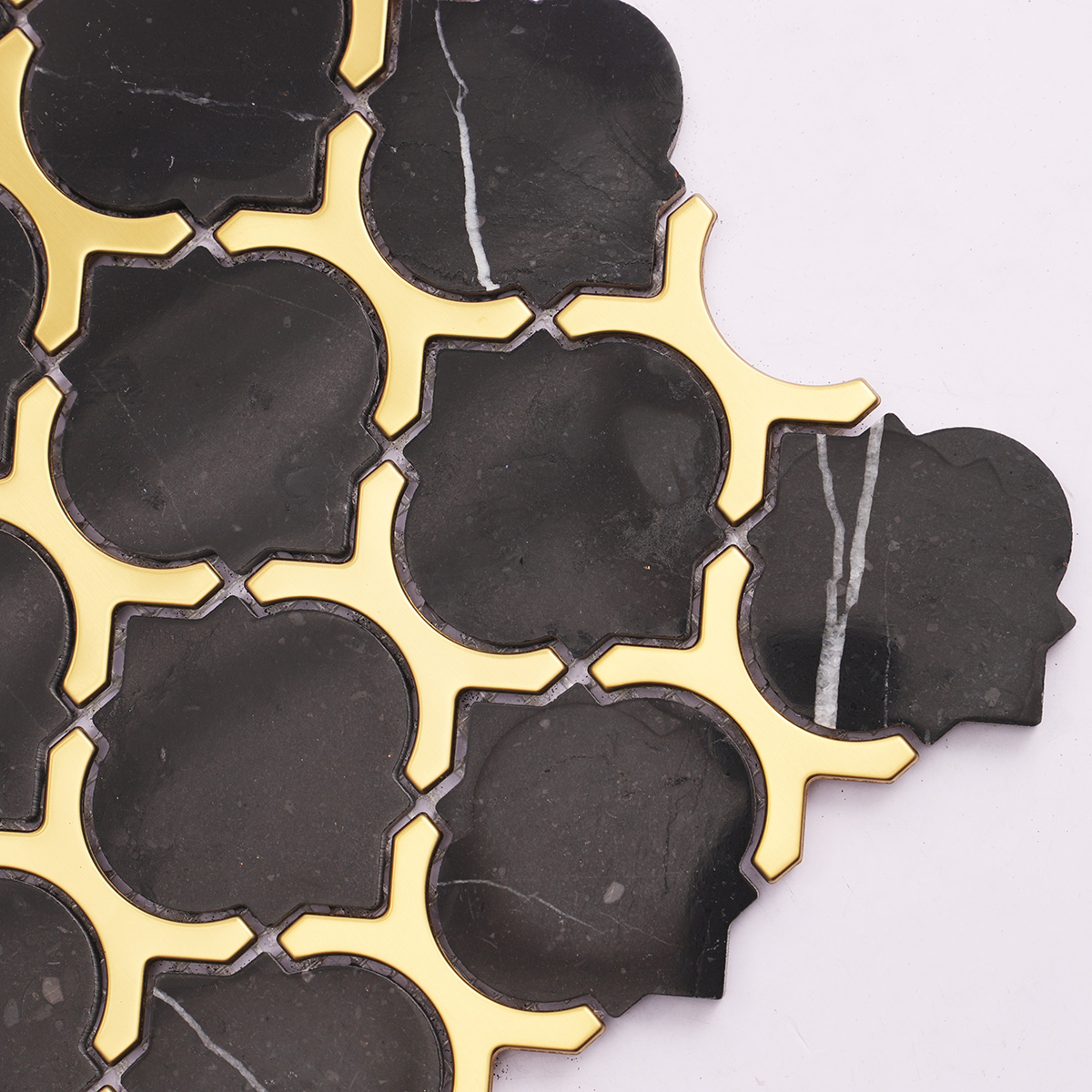 Detailed close-up of black marble and gold stainless steel arabesque mosaic tiles.