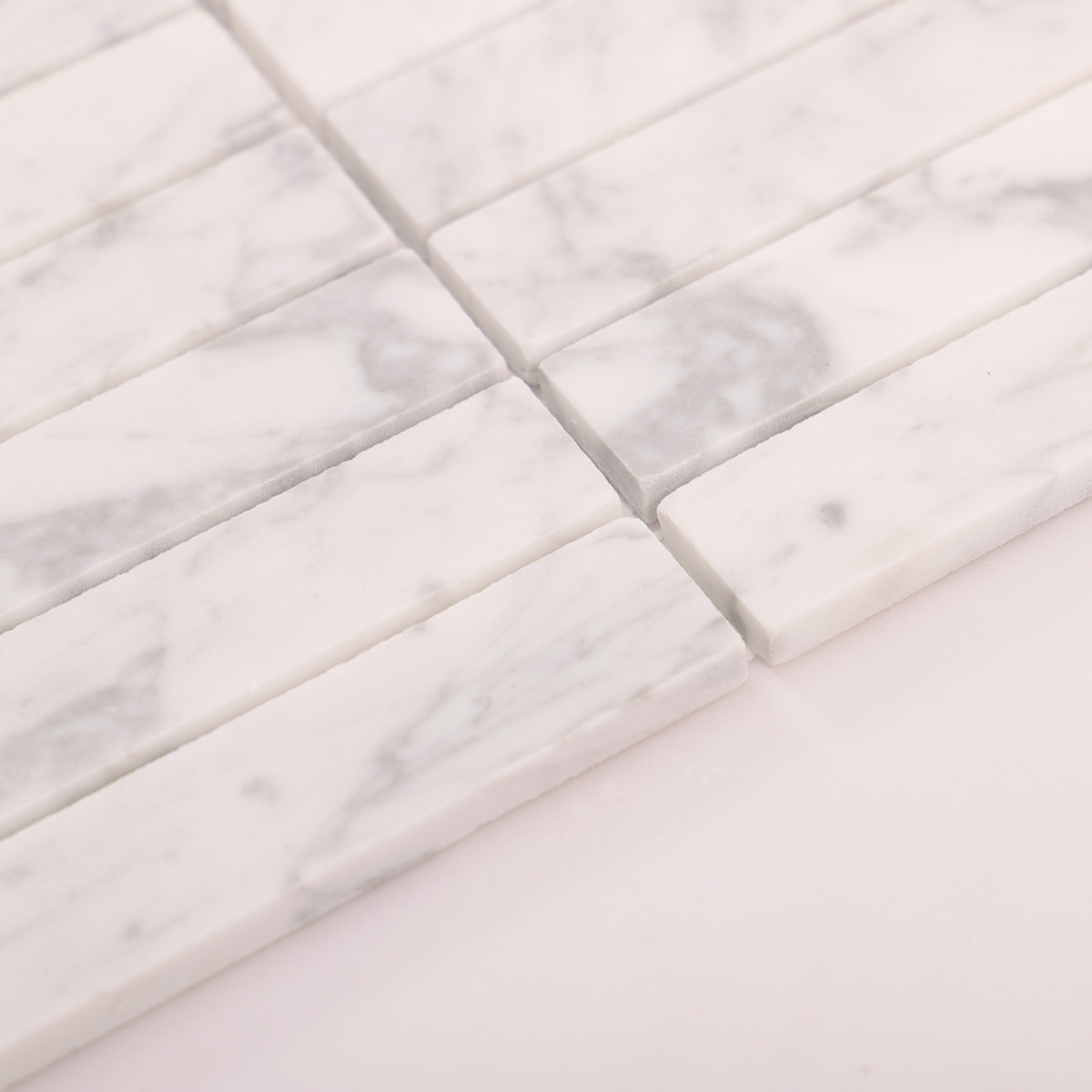Macro close-up side view of Carrara white marble stacked polished mosaic tiles.
