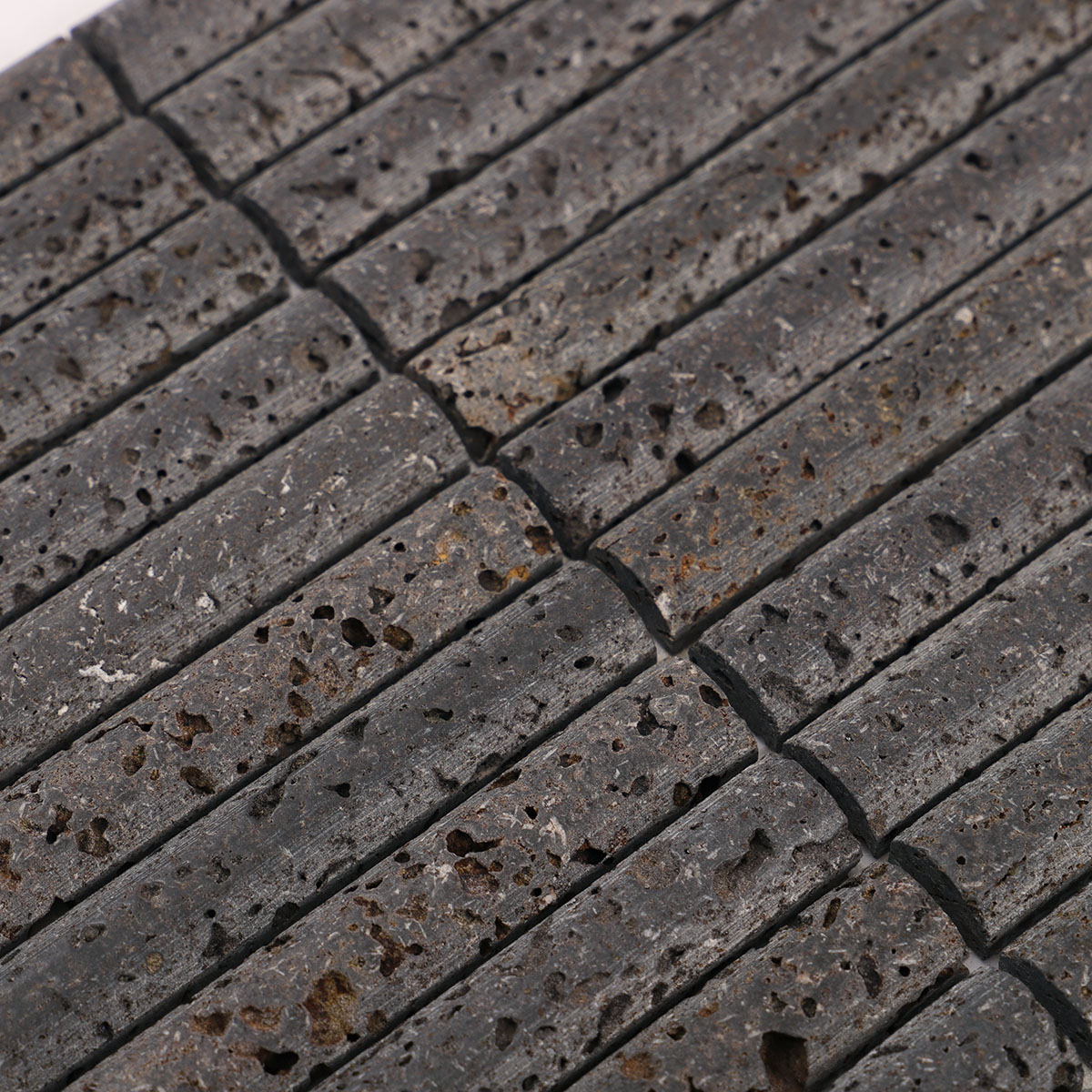 Close-up view of 3D concave fluted strip black lava stone mosaic tiles.