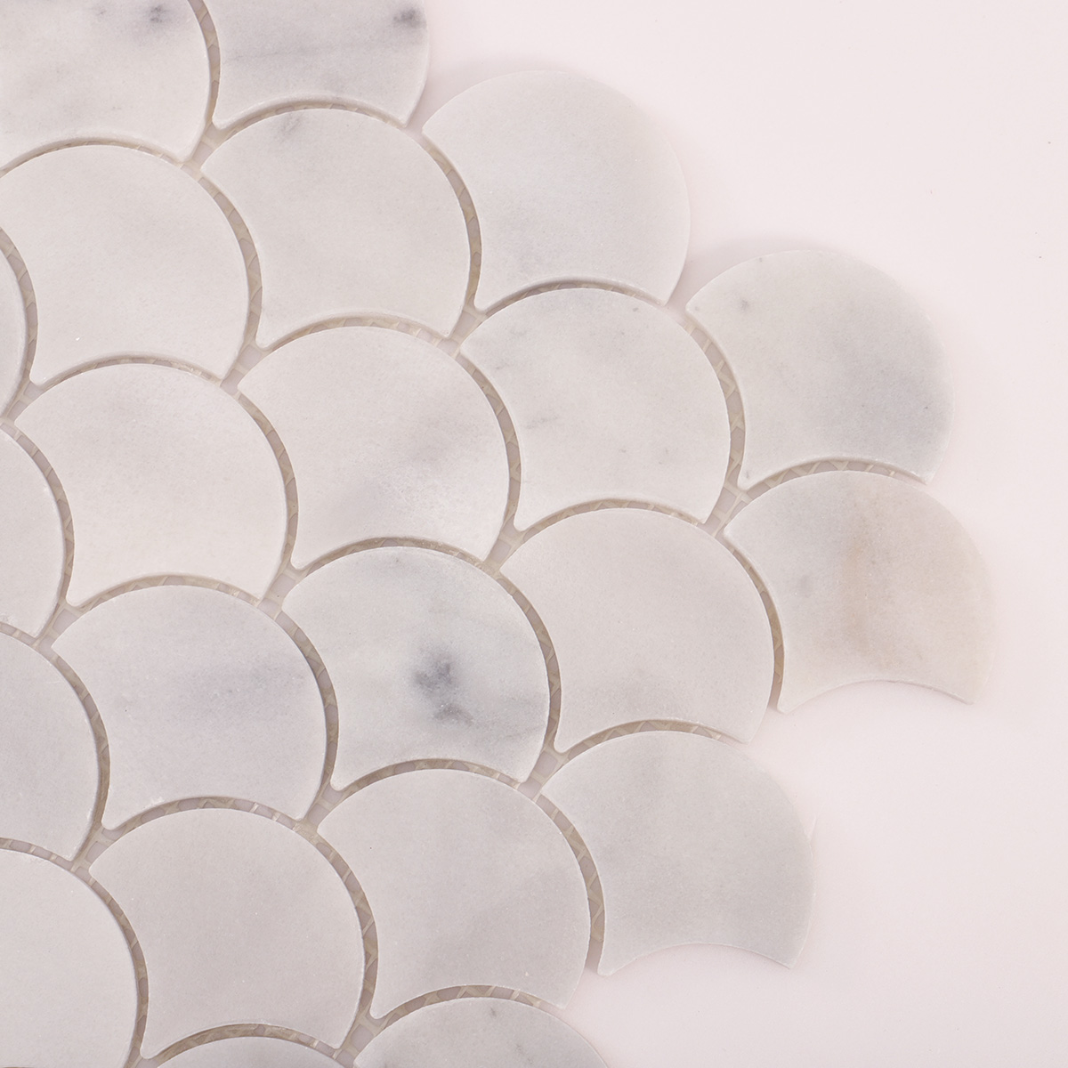 Detailed close-up of fish scale white marble polished mosaic tiles.