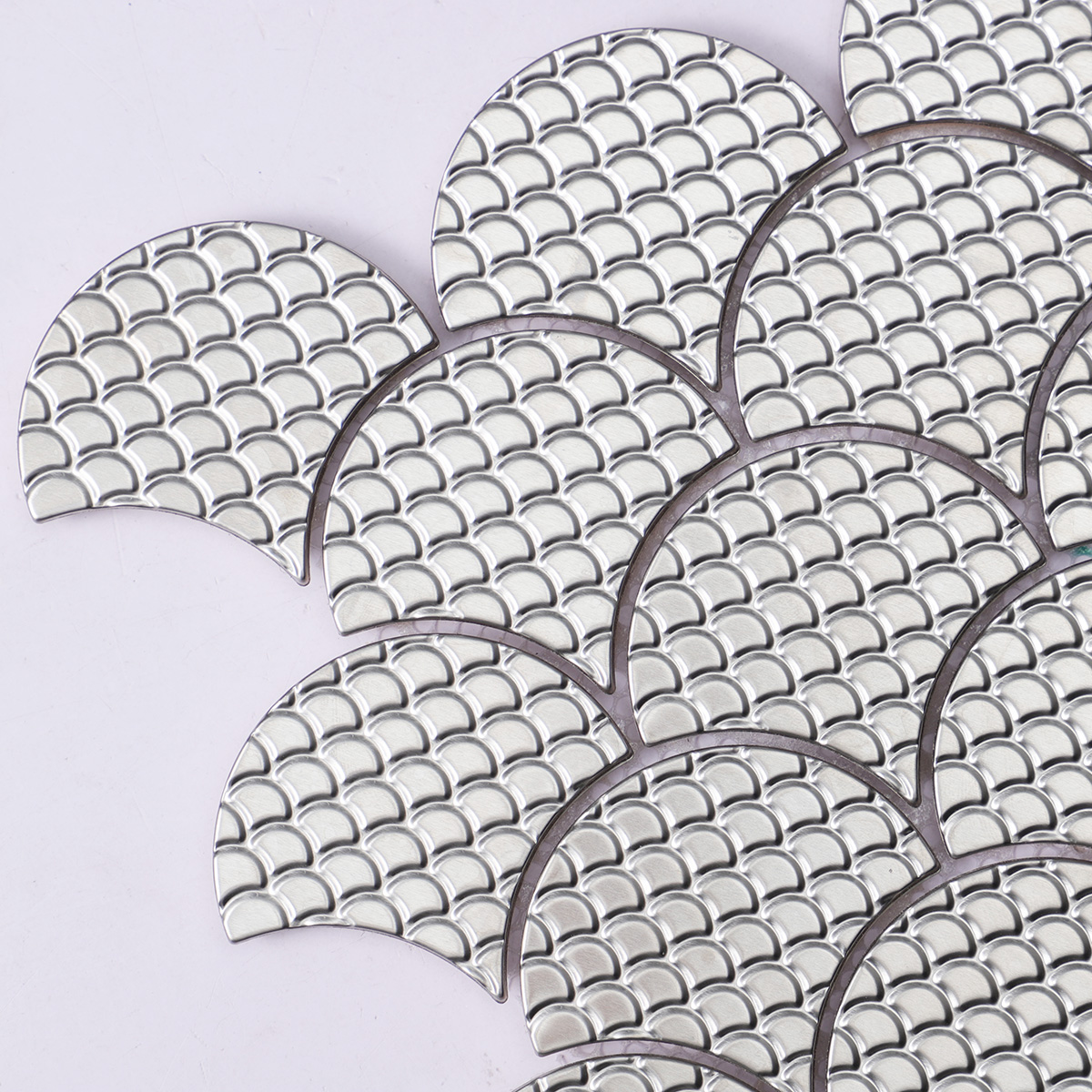 Detailed close-up of silver fish scale stainless steel metal mosaic tiles.