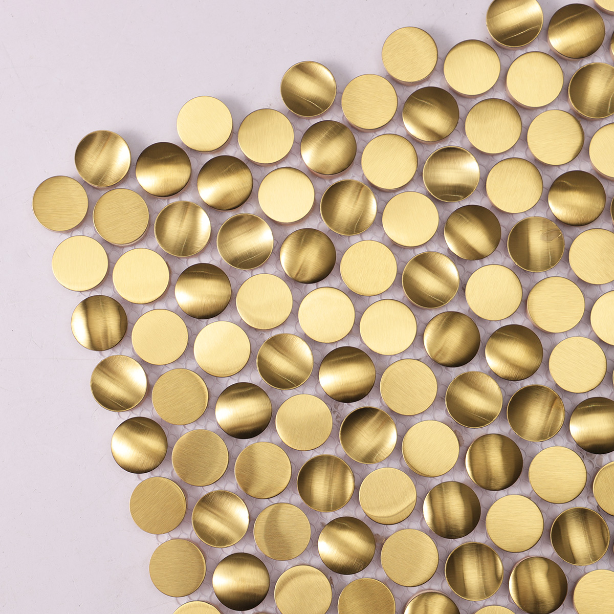 Detailed close-up of 3D gold penny rounds brushed stainless steel mosaic tiles.