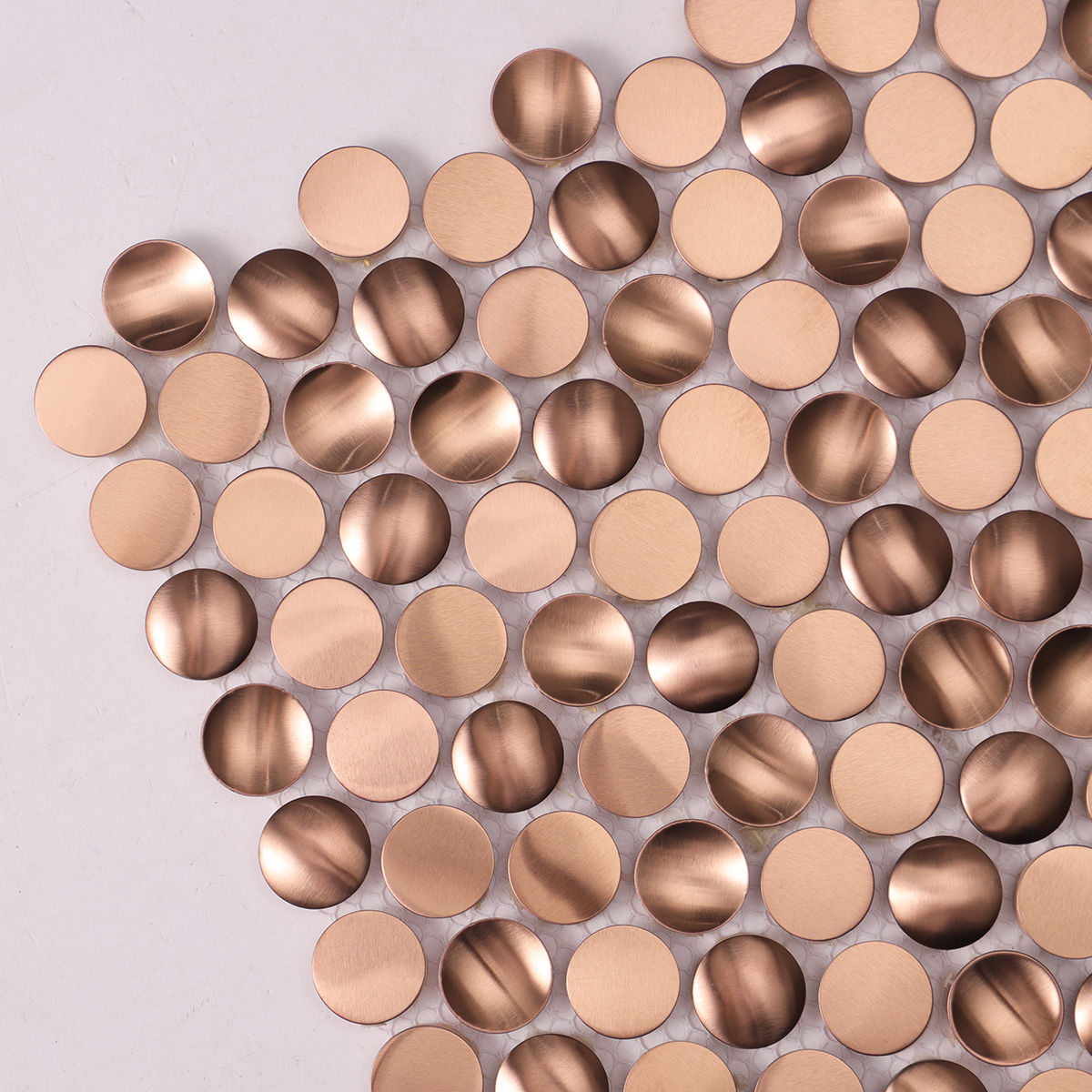 Detailed close-up of penny rounds rose gold 3D stainless steel mosaic tiles.