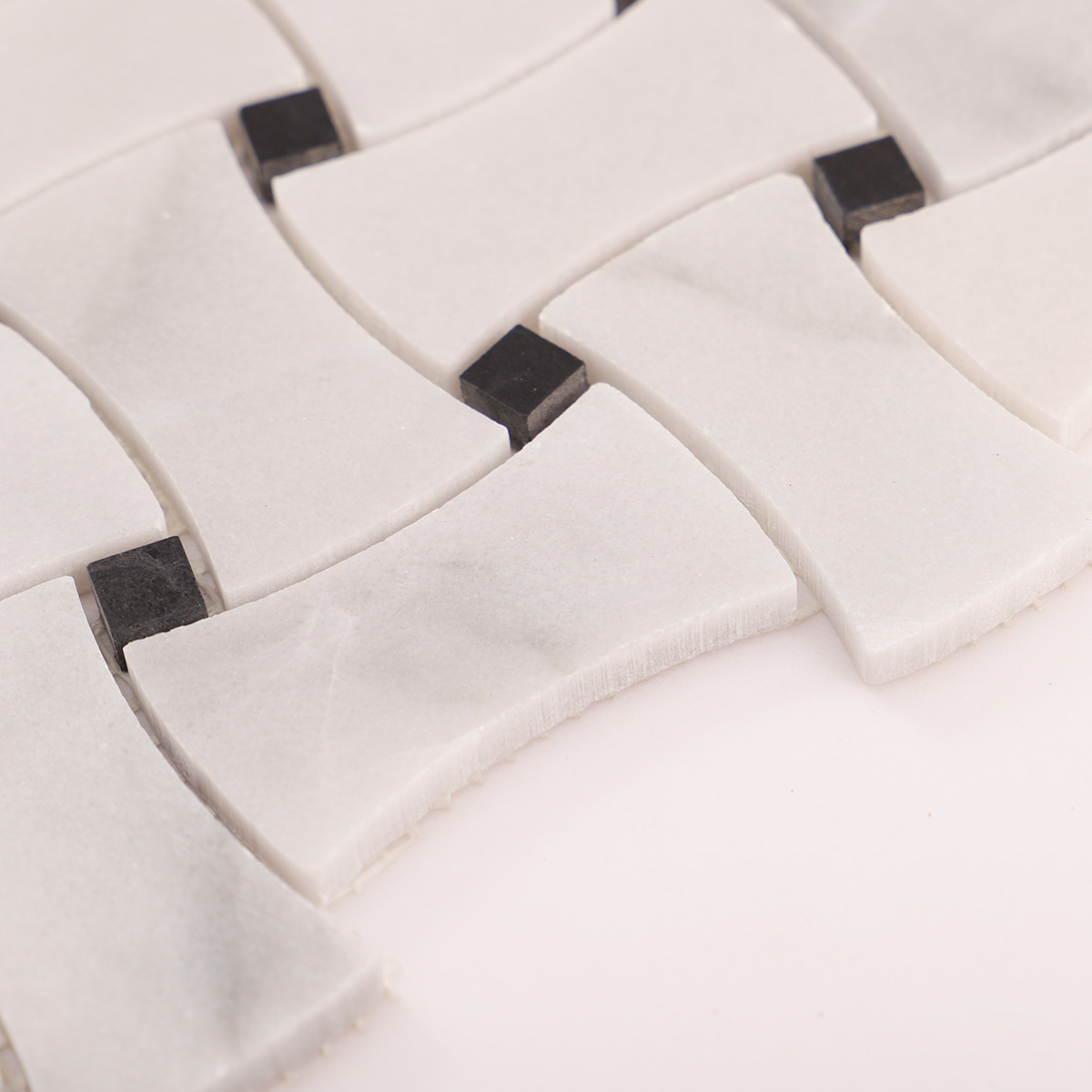 Close-up view of Carrara white basketweave marble mosaic tiles with black dots