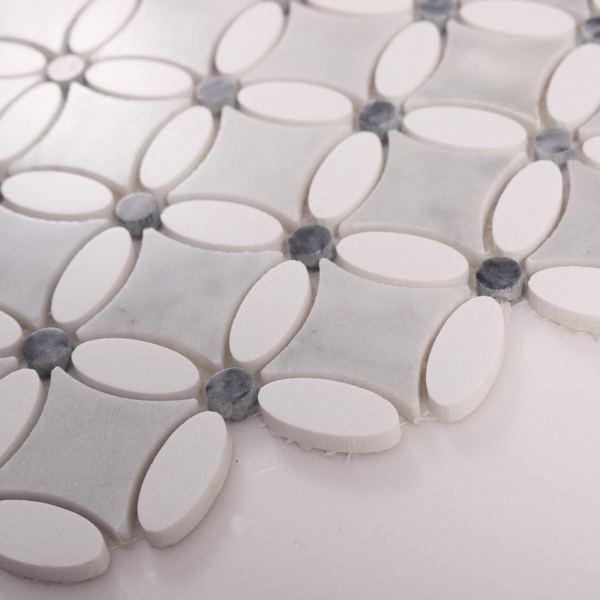Side close-up view of gray and white floral marble mosaic tiles, showing texture and thickness
