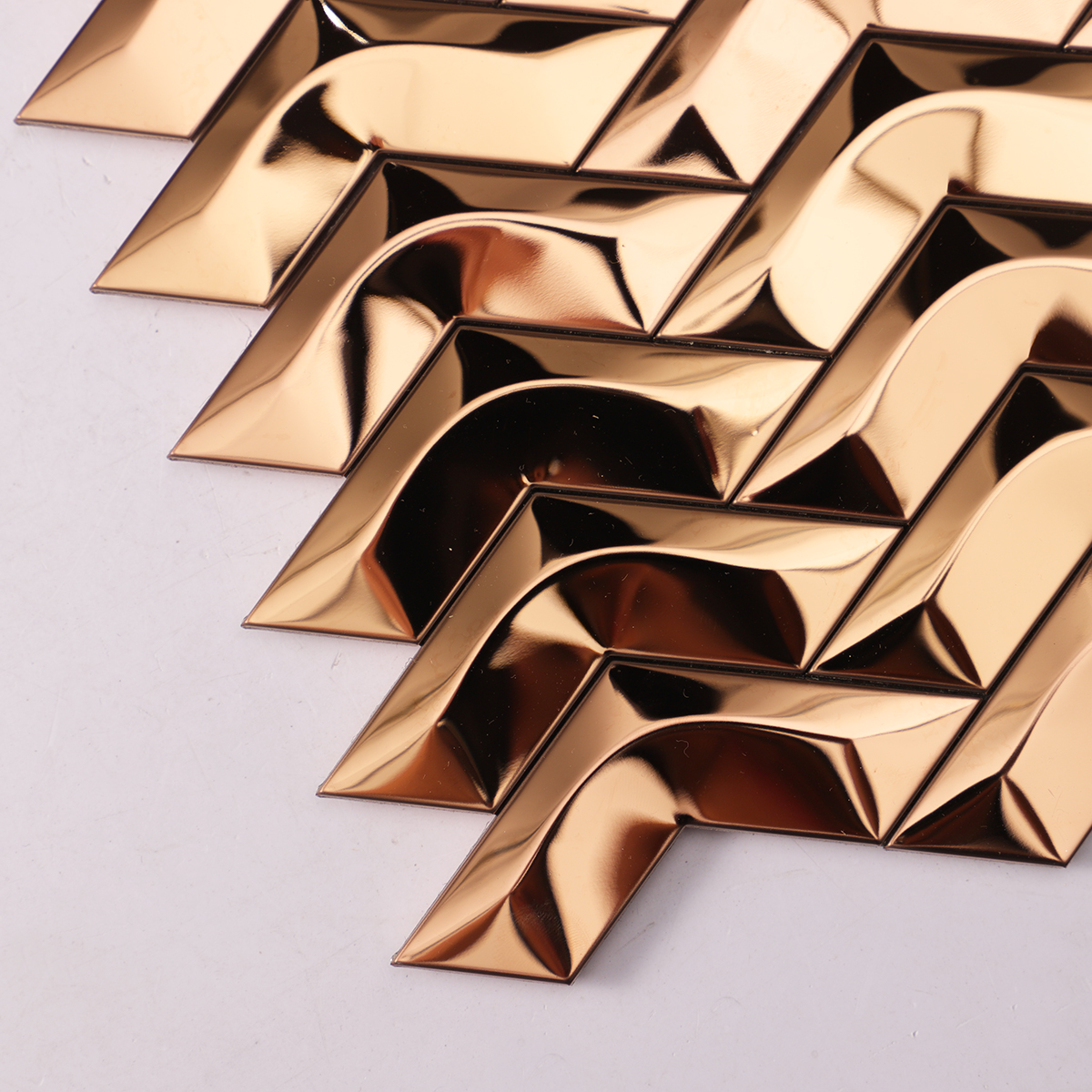 Close-up of 3D Herringbone Rose Gold Mirror Metal Mosaic Wall Tile, texture detail
