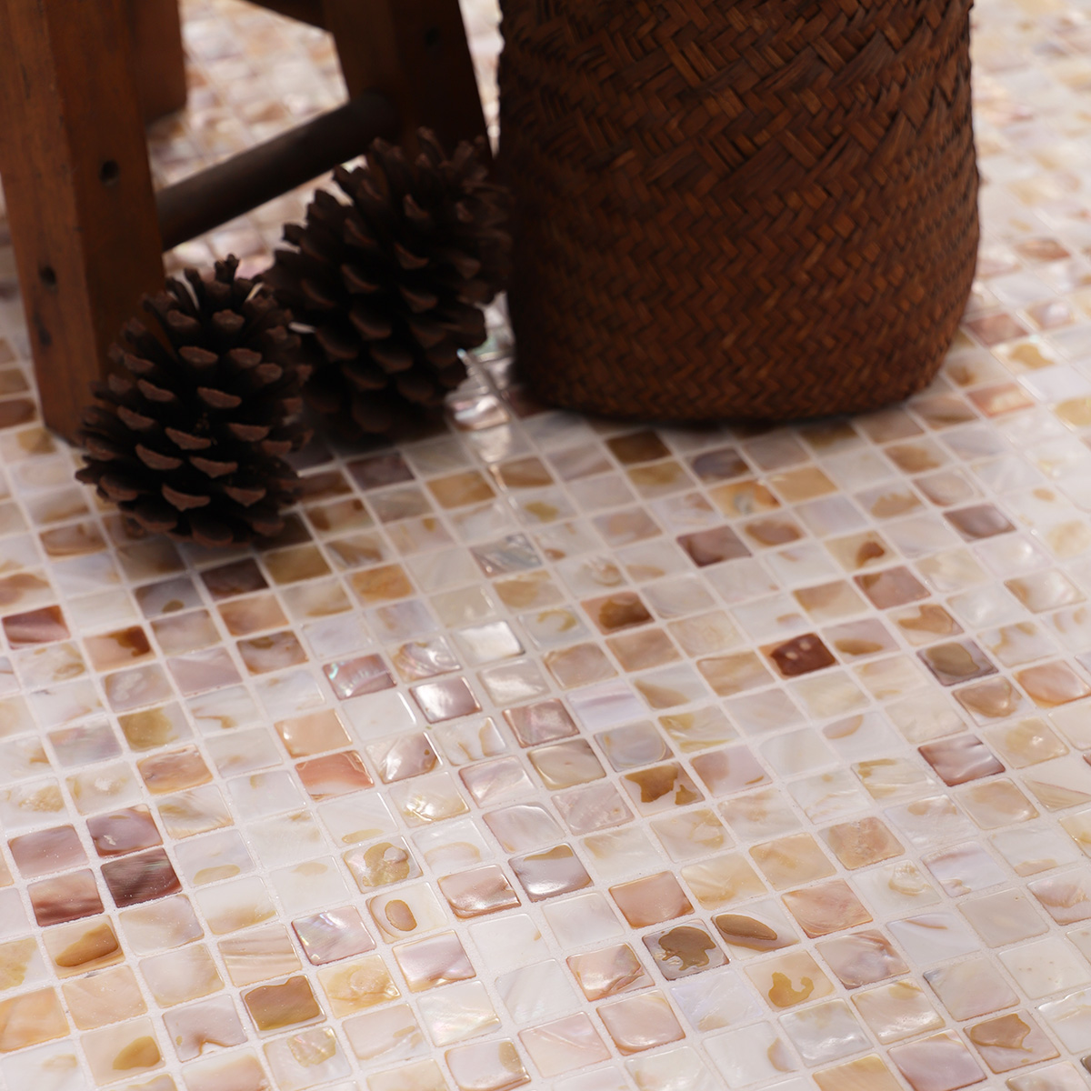 Close-up of beige mini fish scale mother of pearl mosaic tiles with irregular patterns.