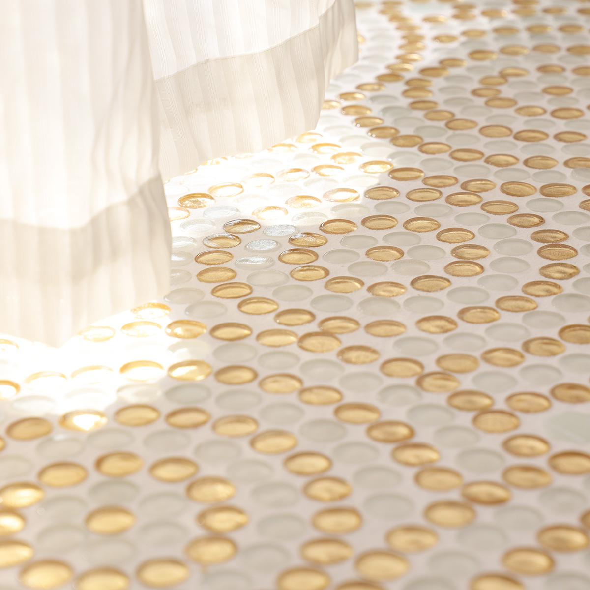  Floor scene with white curtain between circular gold and white mosaic tiles.