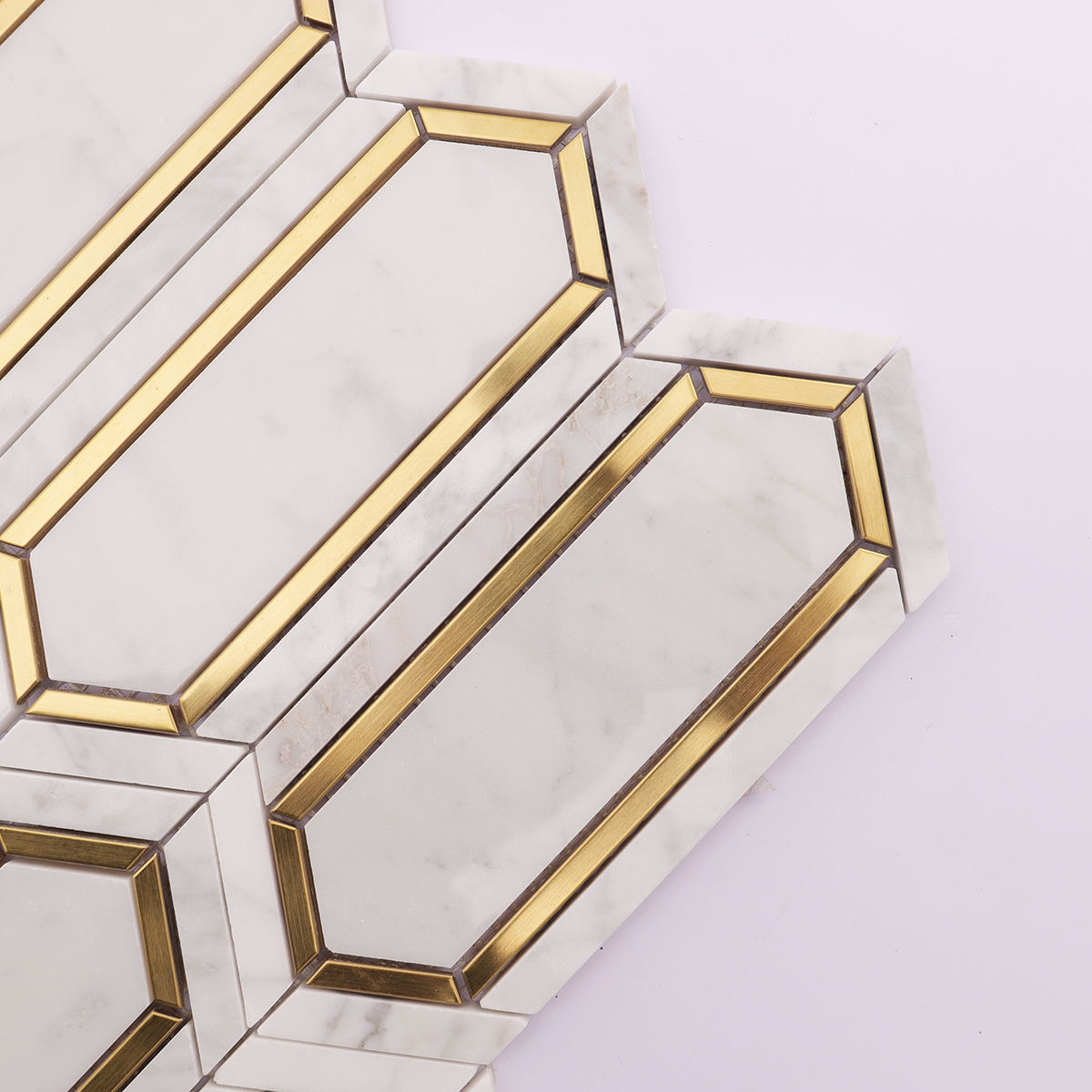 Close-up of the Carrara white marble and gold metal picket mosaic tiles, showing texture.