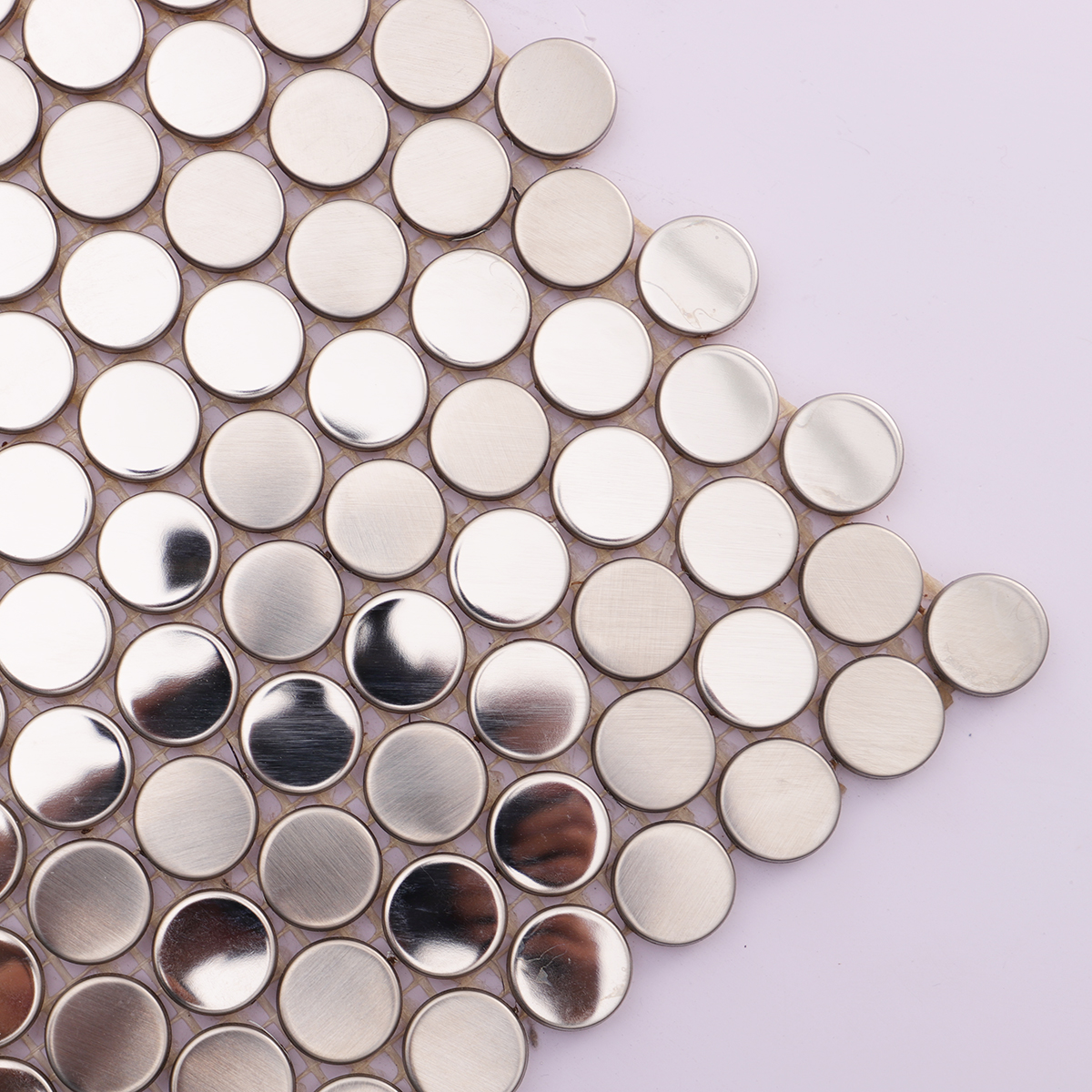 Close-up of alternating brushed and mirror finishes on silver penny tiles.