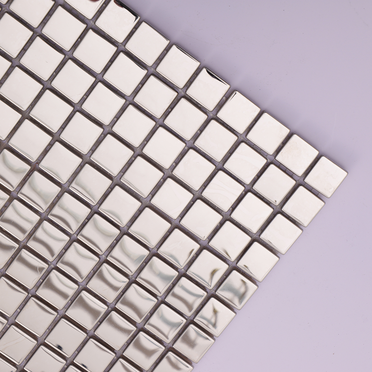 Close-up of the reflective mirror finish on stainless steel square tiles.