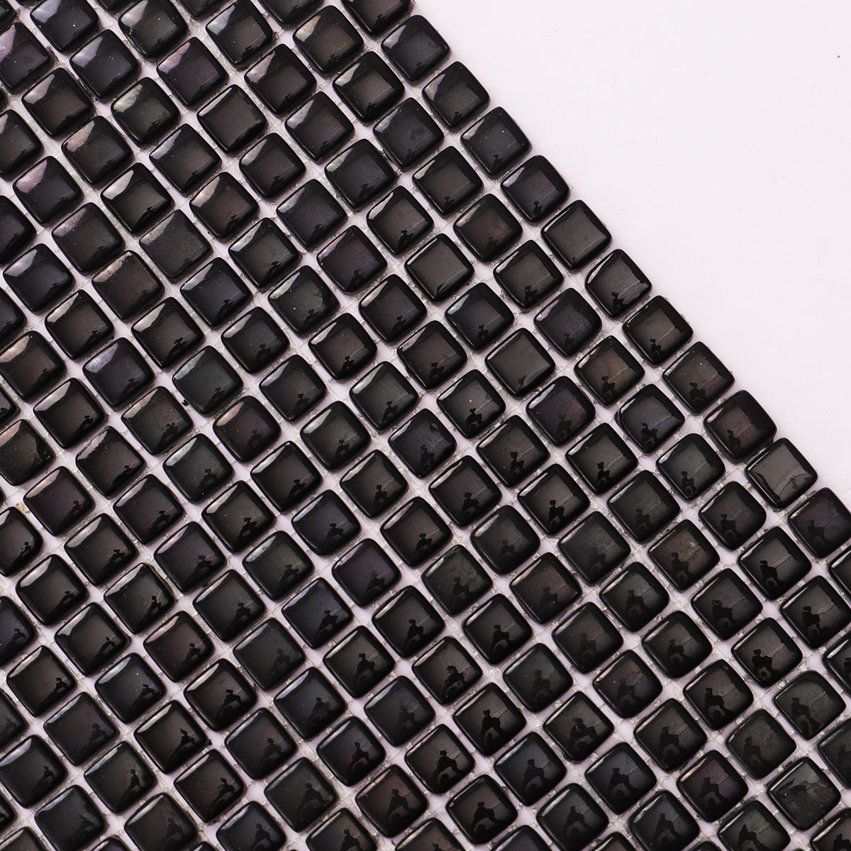 Close-up of tiny black glossy recycled glass mosaic tiles.