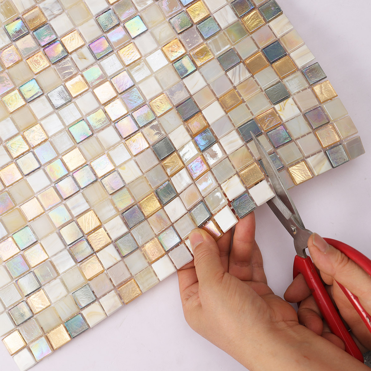Cutting of beige and gold iridescent glass mosaic tiles mixed.