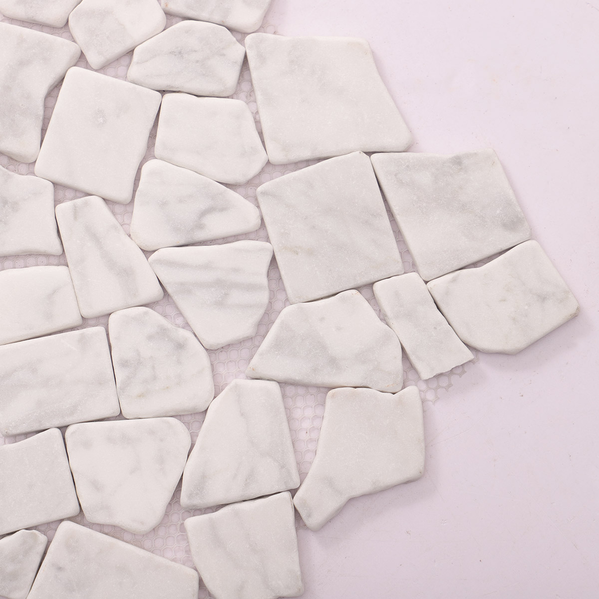 Detailed close-up of cracked white Carrara marble mosaic tile