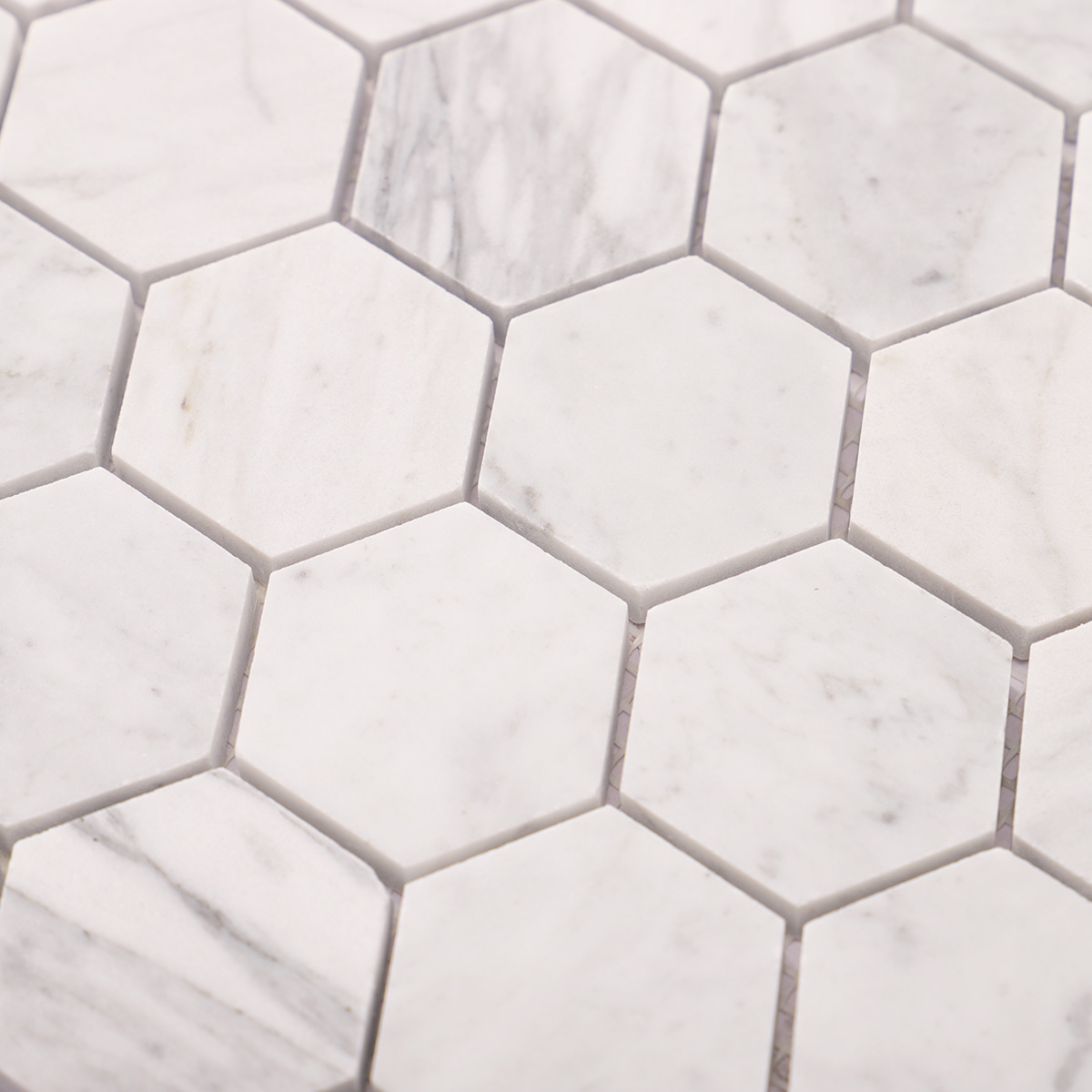 Detailed close-up of Carrara white hexagon marble mosaic tiles.