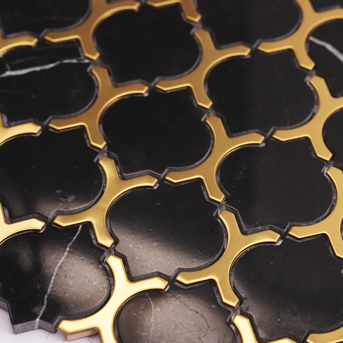 Close-up of black marble and gold stainless steel arabesque mosaic tiles