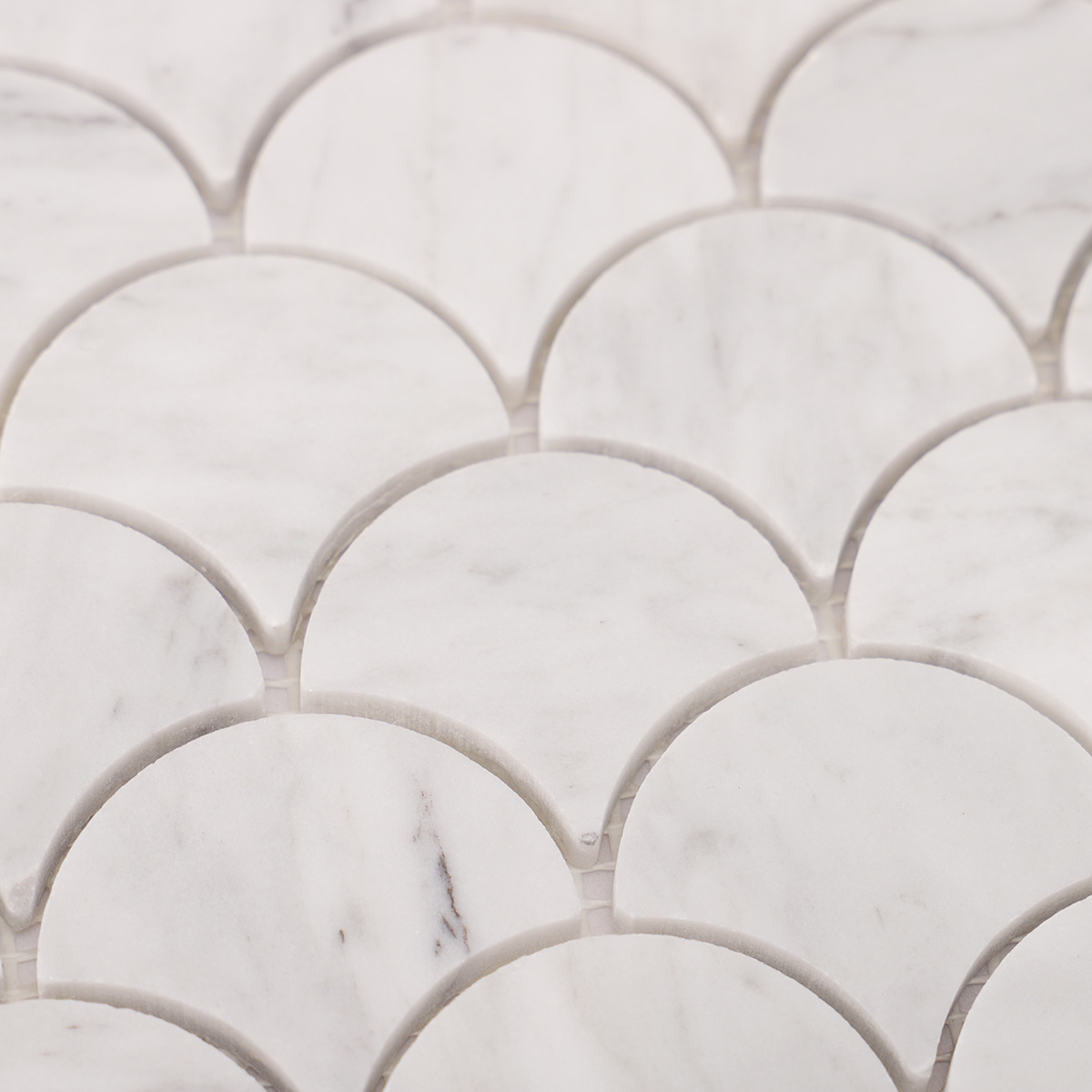 Macro close-up of fish scale fan shape Carrara white marble polished mosaic tiles.