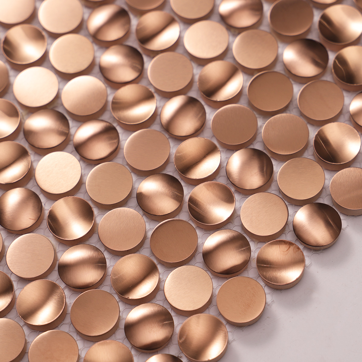 Close-up of penny rounds rose gold 3D stainless steel mosaic tiles.