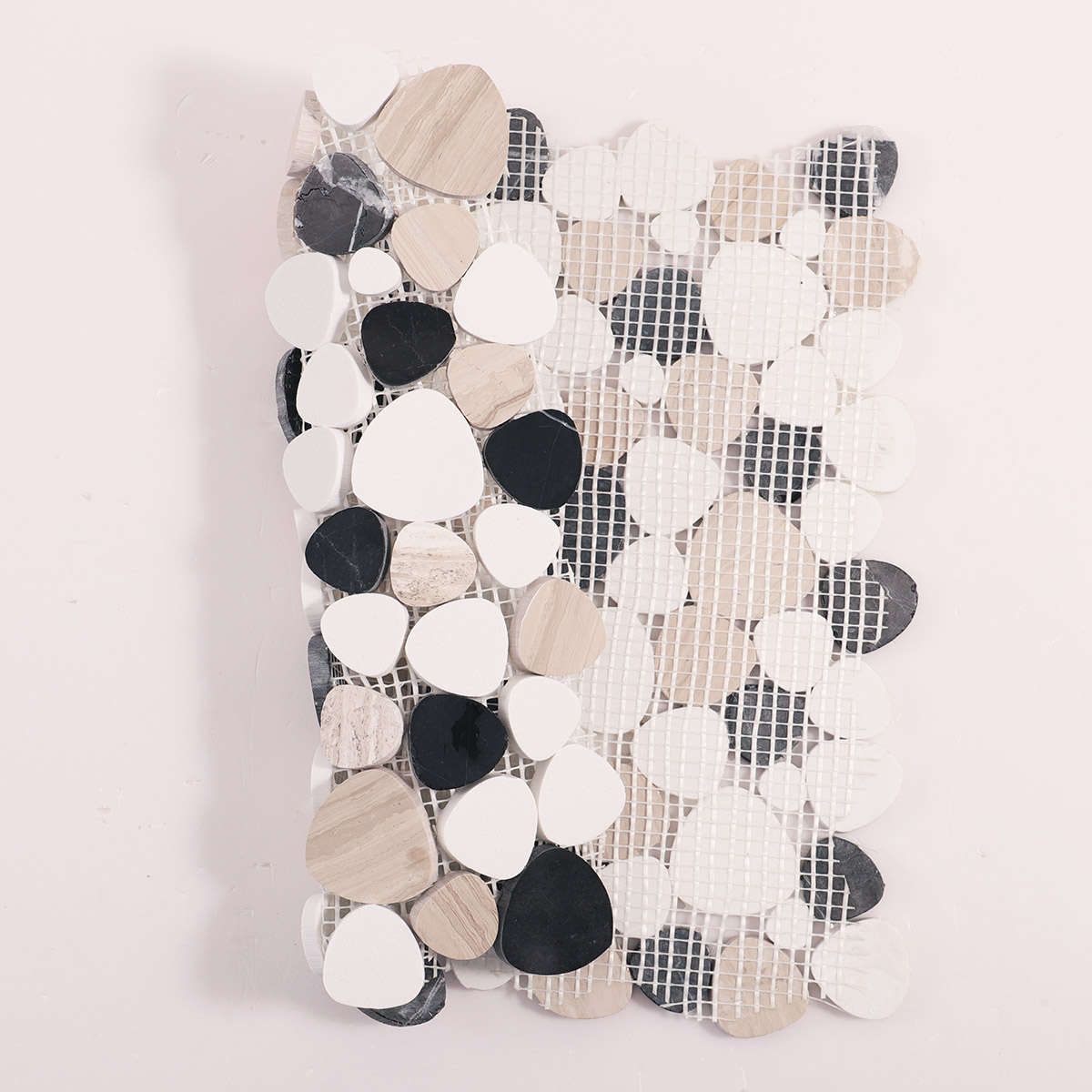 Folded back side of white and black flat pebble stone mosaic tiles.