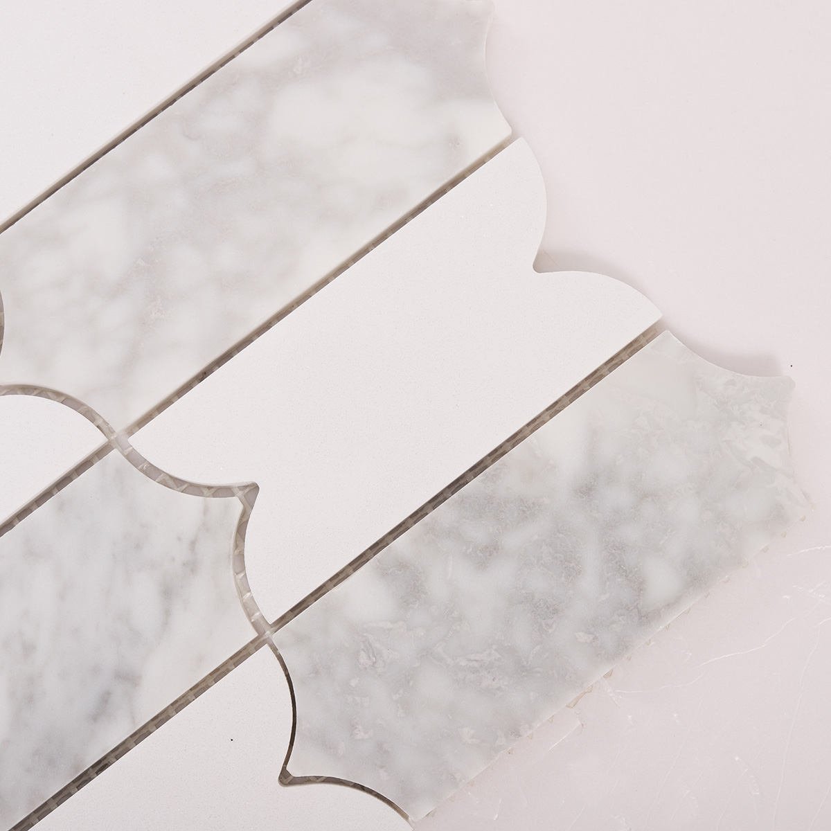 Detailed close-up of Carrara white natural stone mosaic tiles.